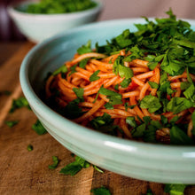 Load image into Gallery viewer, Close up of turquoise past bowl with spaghetti sprinkled with parsley on a wooden board with a turquoise bowl in the background