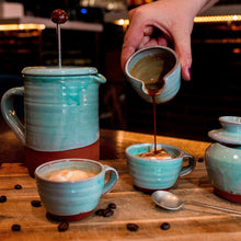 Load image into Gallery viewer, Turquoise cafetiere with 2 espresso cups and coffee being poured from a turquoise mini jug.
