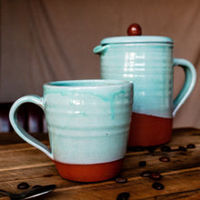 Load image into Gallery viewer, Large turquoise mug and cafetiere on a wooden board with coffee beans scattered around.