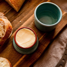 Load image into Gallery viewer, French butter keeper, turquoise glaze, butter in the lid sitting on a wooden board with buttered bread.