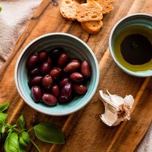 Load image into Gallery viewer, Medium turquoise bowl with black olives and a small turquoise bowl with olive oil and balsamic on a chopping board with mini bread slices and basil.